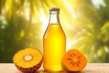 Sebotol jus kuning cerah yang dibuat dari mangga dan nanas, dengan kepingan buah tropika.